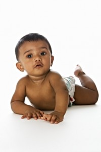 Adorable Indian baby lying on floor and looking straigth, isolated on white background.